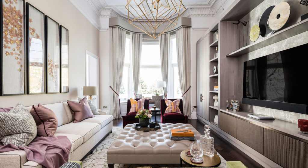 Living room with warm textiles, large, tufted ottoman, drapery, and open shelves