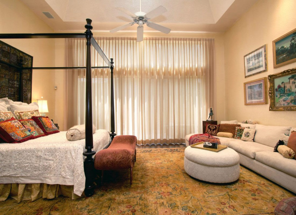 Bedroom featuring warm colors and layers of textiles including assorted throw pillows